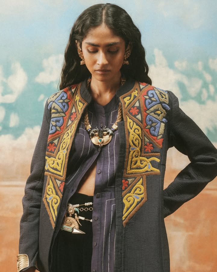 A quilted blue jacket is worn over a silk long dress in this silhouette